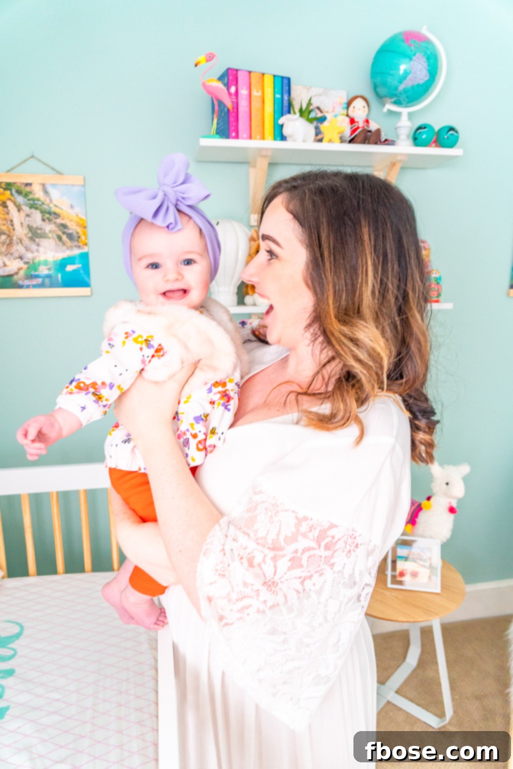 Mother and daughter share a tender moment by the crib in their beautifully designed travel-inspired nursery.