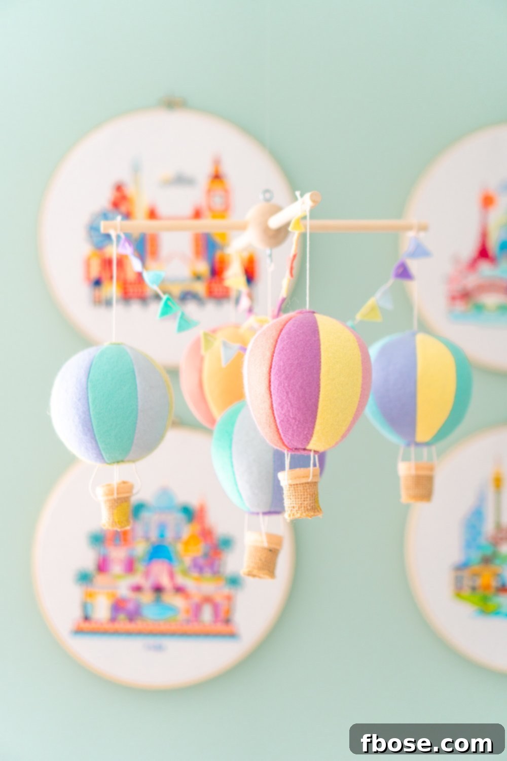 A charming felt hot air balloon mobile gracefully hangs in a baby nursery, adding a whimsical touch to the decor.