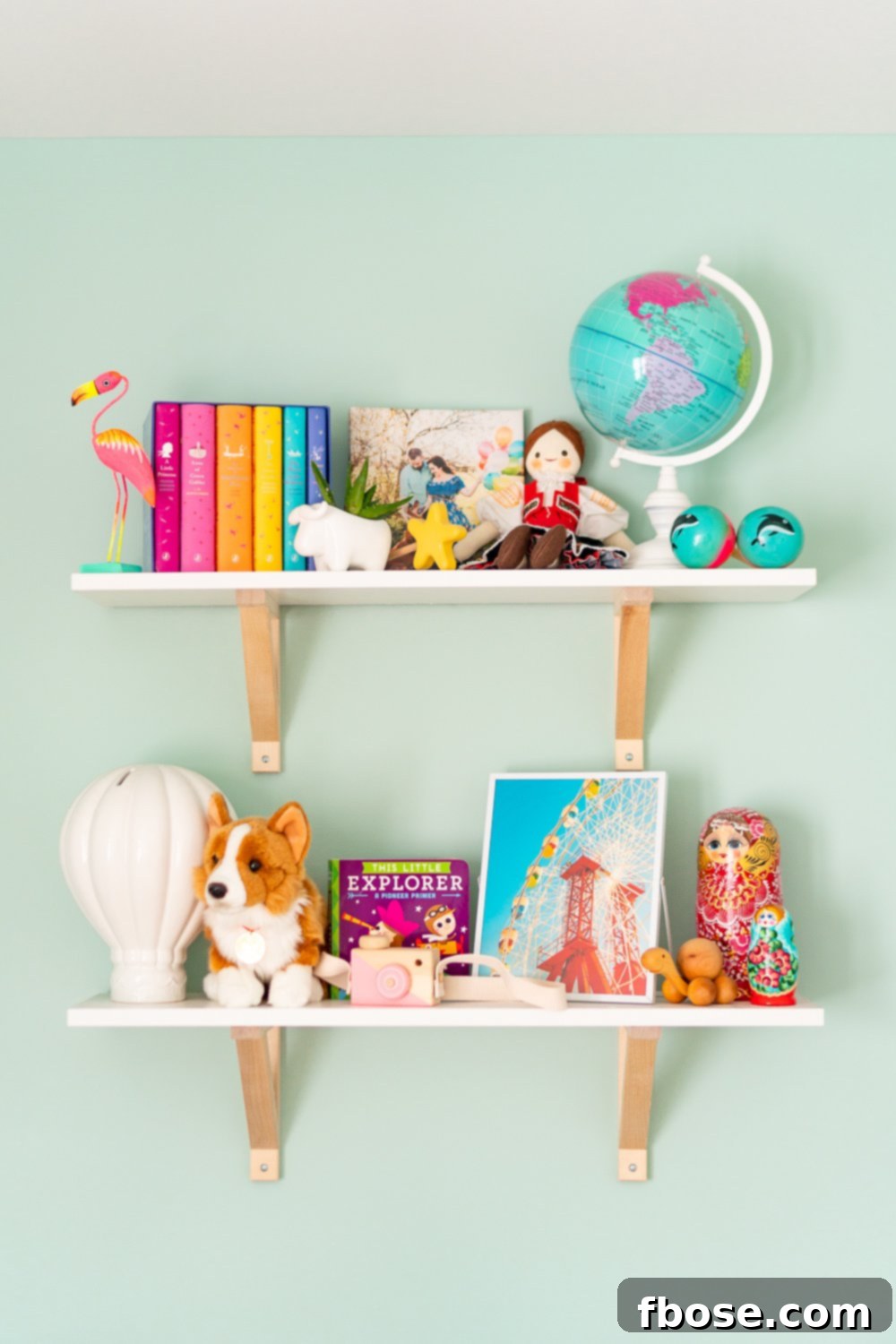 Artfully arranged travel-inspired nursery decorations adorn white shelves, showcasing a blend of global treasures and whimsical pieces.
