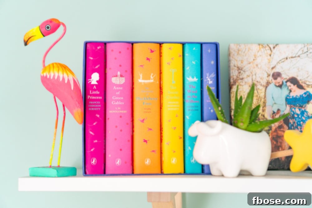 A stack of colorful Puffin Classic books and a modern plant holder on a shelf in a baby nursery, combining literature and natural elements.