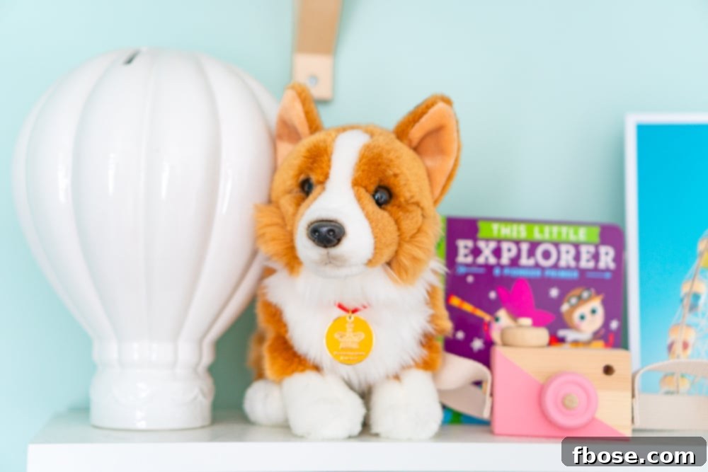 A carefully arranged shelf in a travel-themed nursery, featuring a piggy bank, a corgi toy, and a wooden camera, all contributing to the global decor.