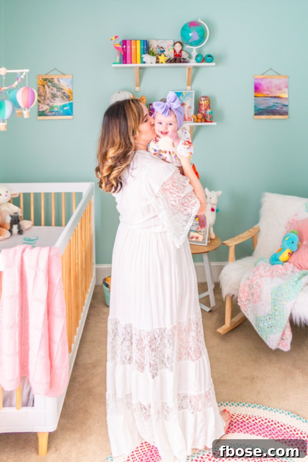 A loving mother holds her baby girl in the serene setting of their travel-inspired nursery, surrounded by thoughtful decor.