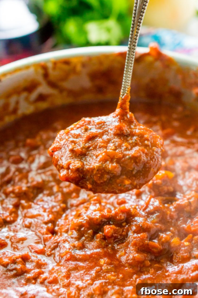 Close-up of hearty spaghetti bolognese sauce simmering in a saucepan.