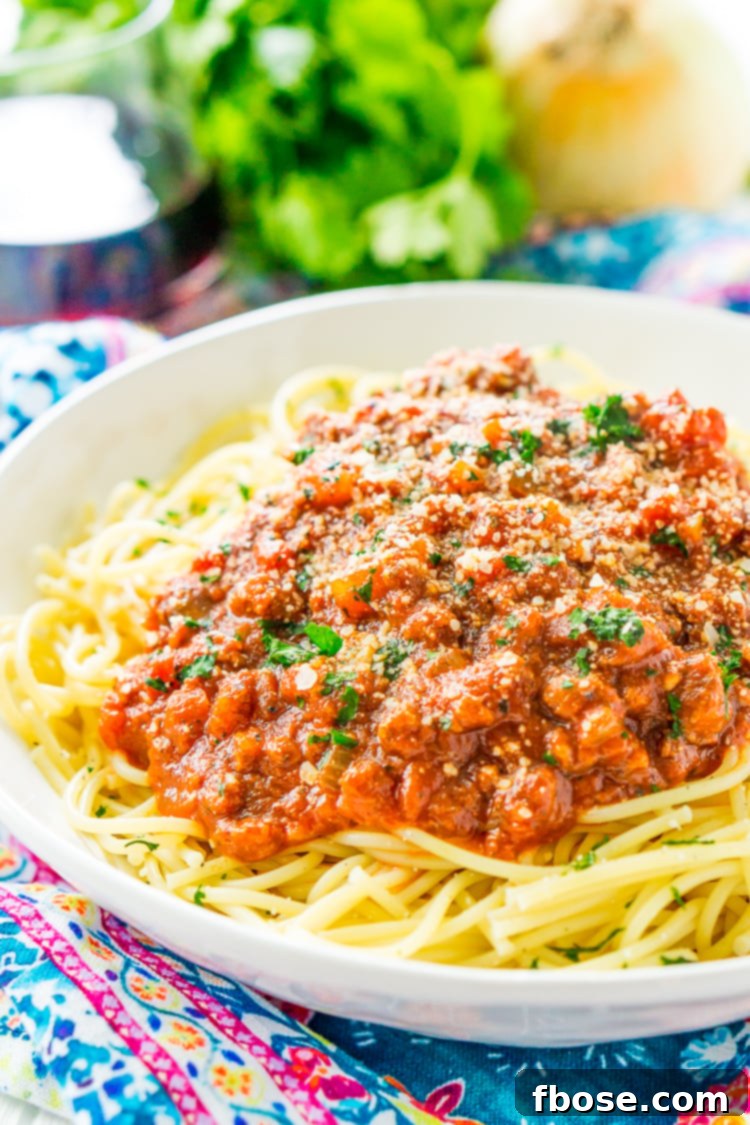 A bowl of spaghetti bolognese garnished with fresh basil leaves and grated parmesan cheese.