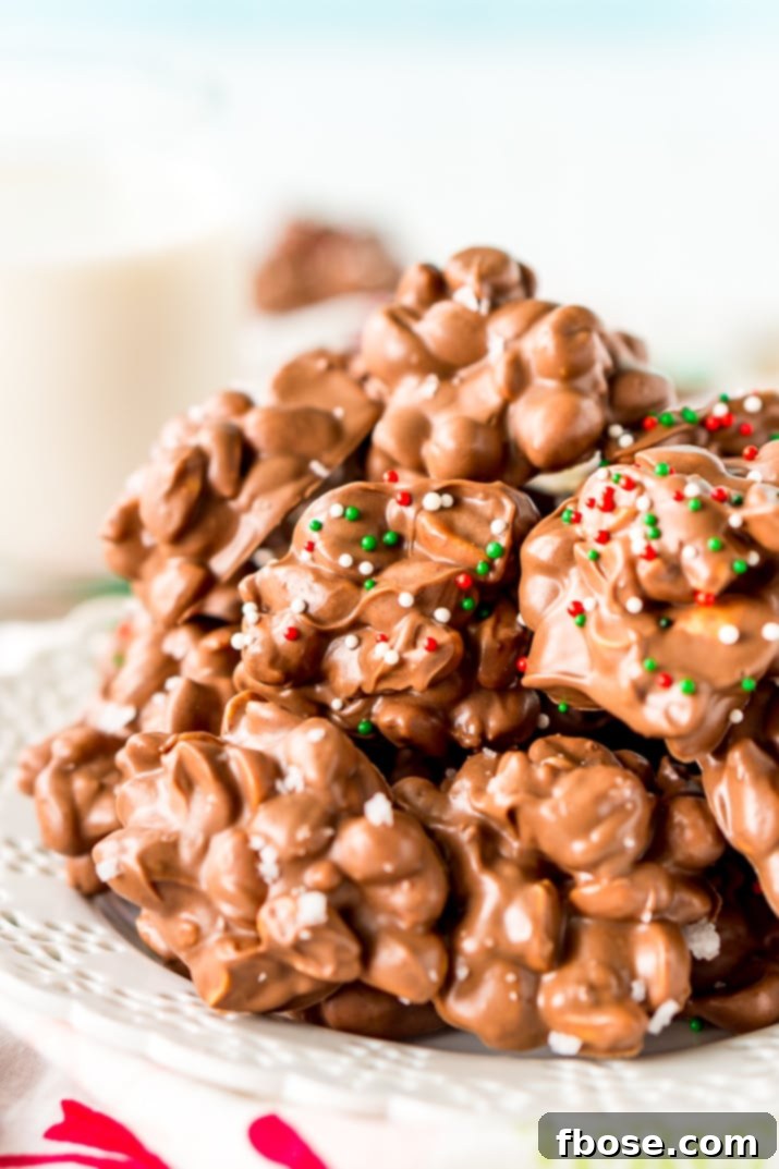 Crockpot Candy is loaded with peanuts, almond bark, and lots of chocolate and super easy to make in the slow cooker! Topped with some festive sprinkles, this pop-in-your-mouth treat is perfect for sharing during the holiday season.