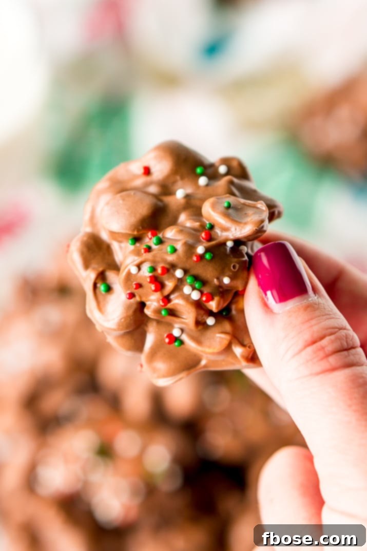 Crockpot Candy is loaded with peanuts, almond bark, and lots of chocolate and super easy to make in the slow cooker! Topped with some festive sprinkles, this pop-in-your-mouth treat is perfect for sharing during the holiday season.