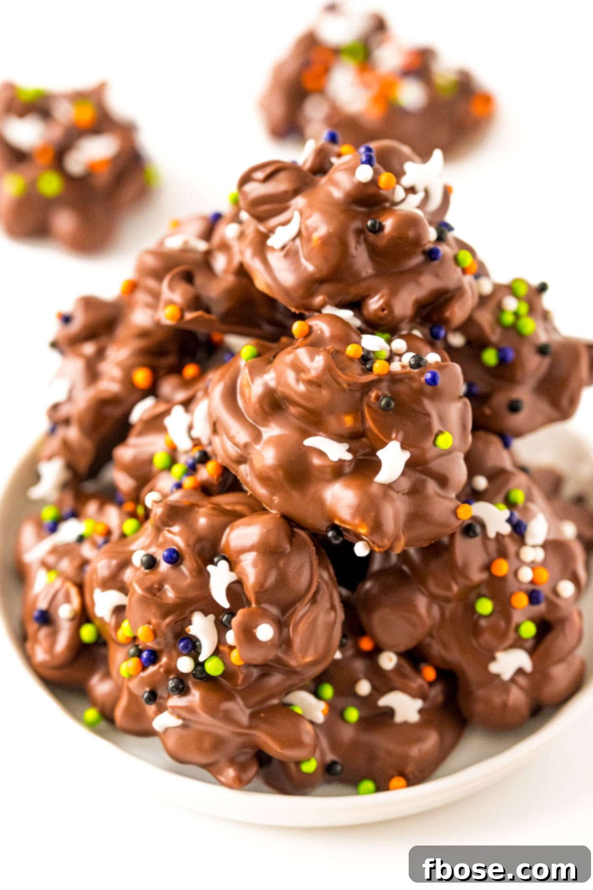 A plate filled with crockpot candy decorated with halloween sprinkles.
