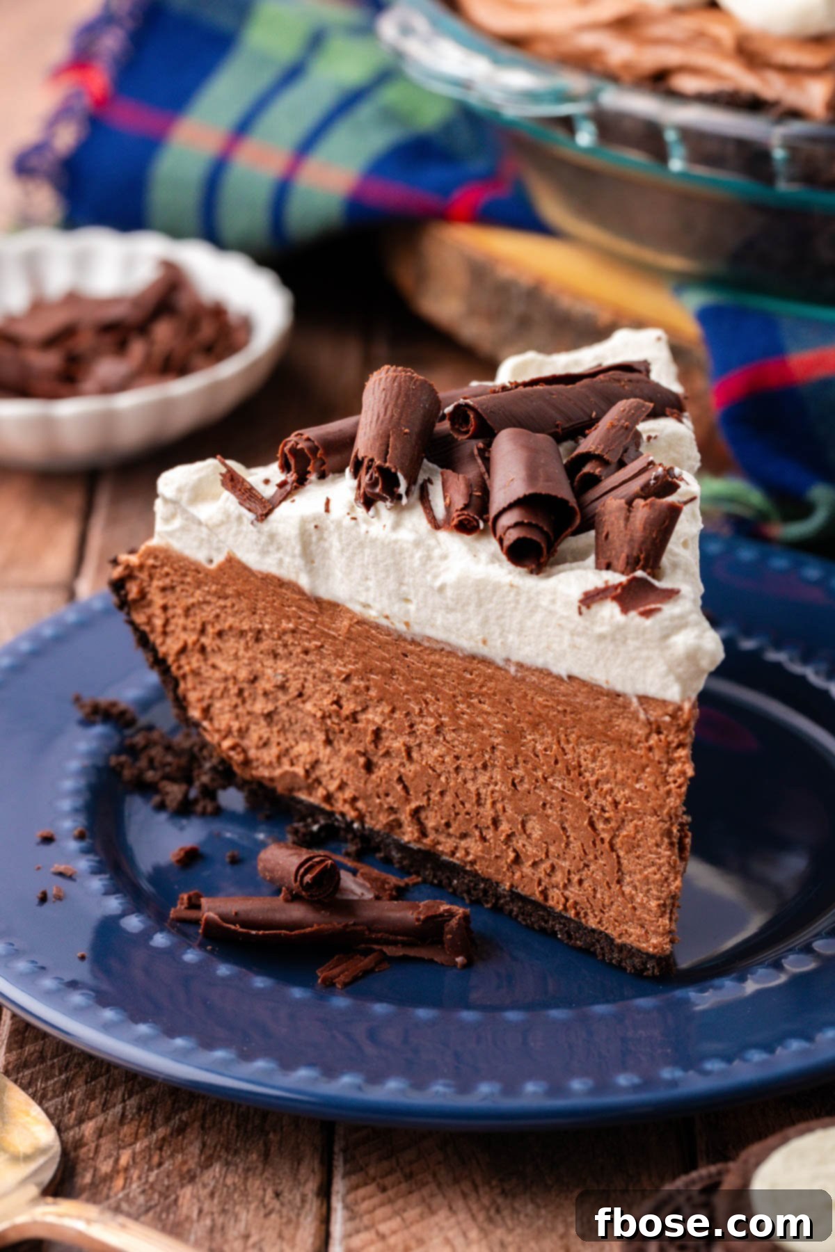 A slice of chocolate french silk pie on a blue plate, garnished with chocolate curls.