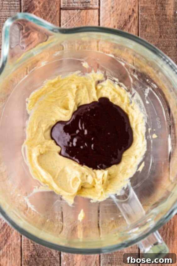 Melted chocolate being added to butter in a mixing bowl.