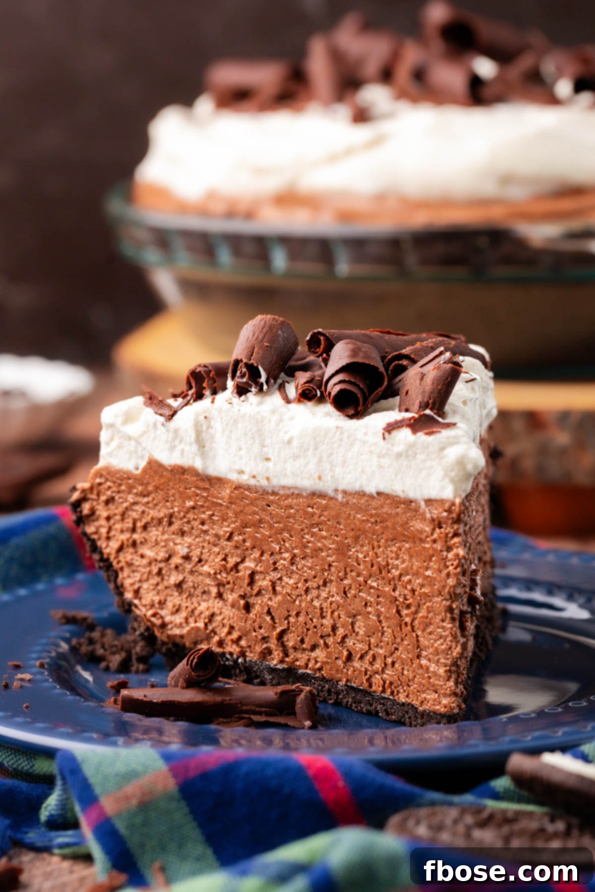 Close up of a slice of French Silk Pie with a generous swirl of whipped cream topping and chocolate curls.