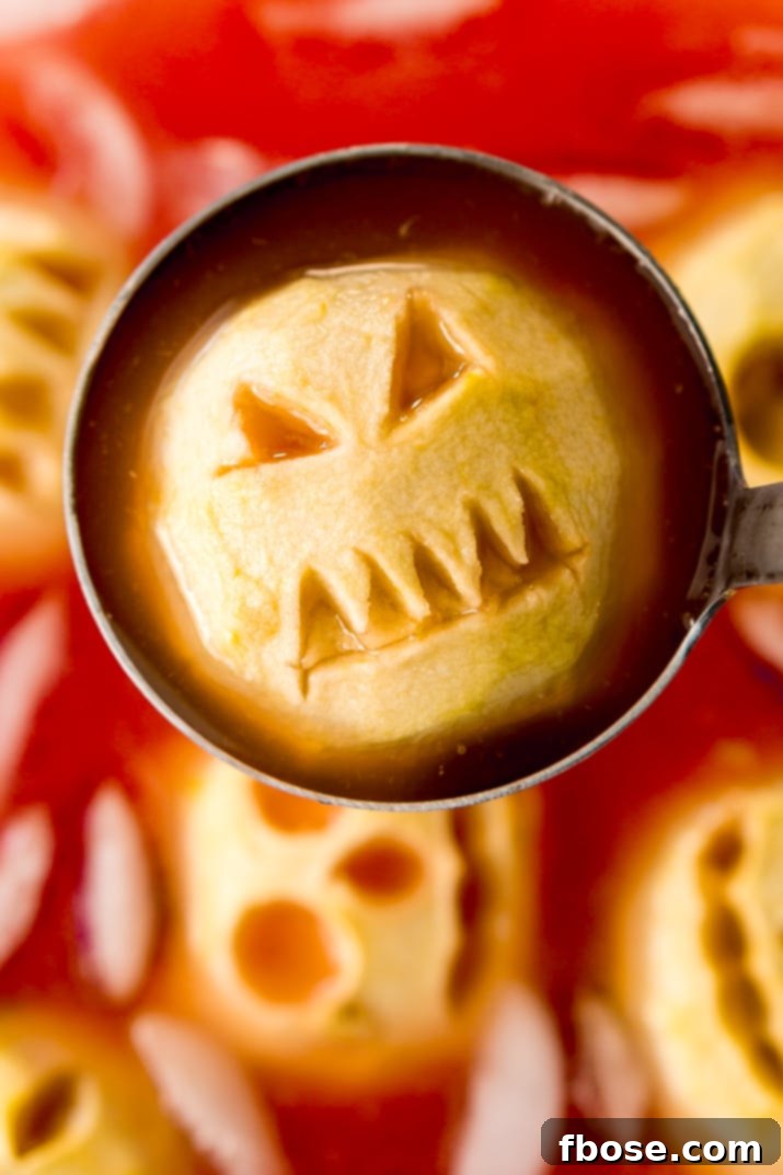 Several glasses of Shrunken Head Party Punch displayed with a large punch bowl in a Halloween setting, ready for guests.