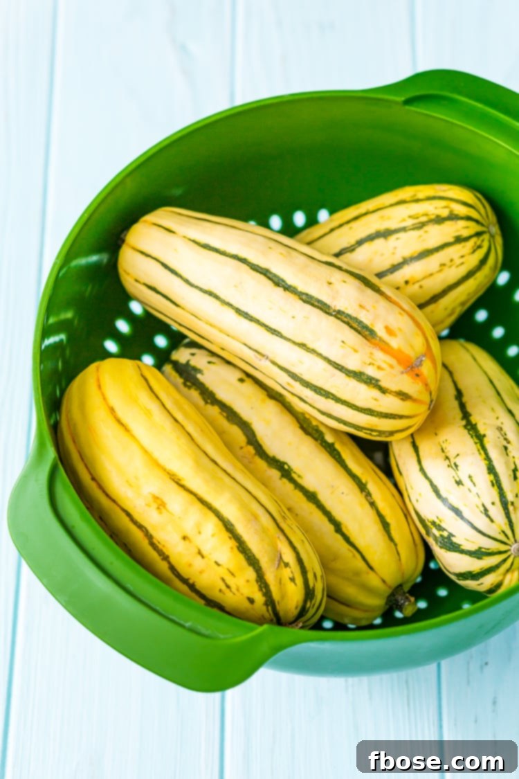 Sweet Roasted Delicata Squash 3 Whole and halved delicata squash on a wooden cutting board.