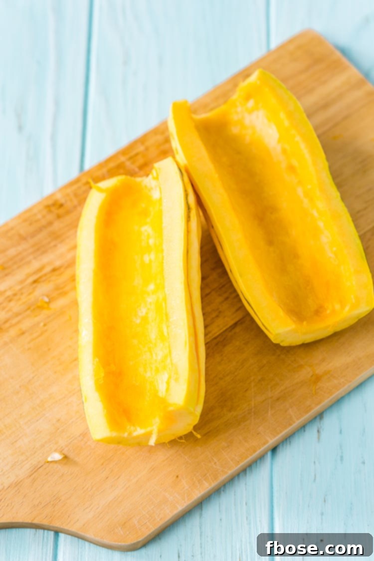 Sweet Roasted Delicata Squash 6 A spoon scooping seeds from a halved delicata squash.