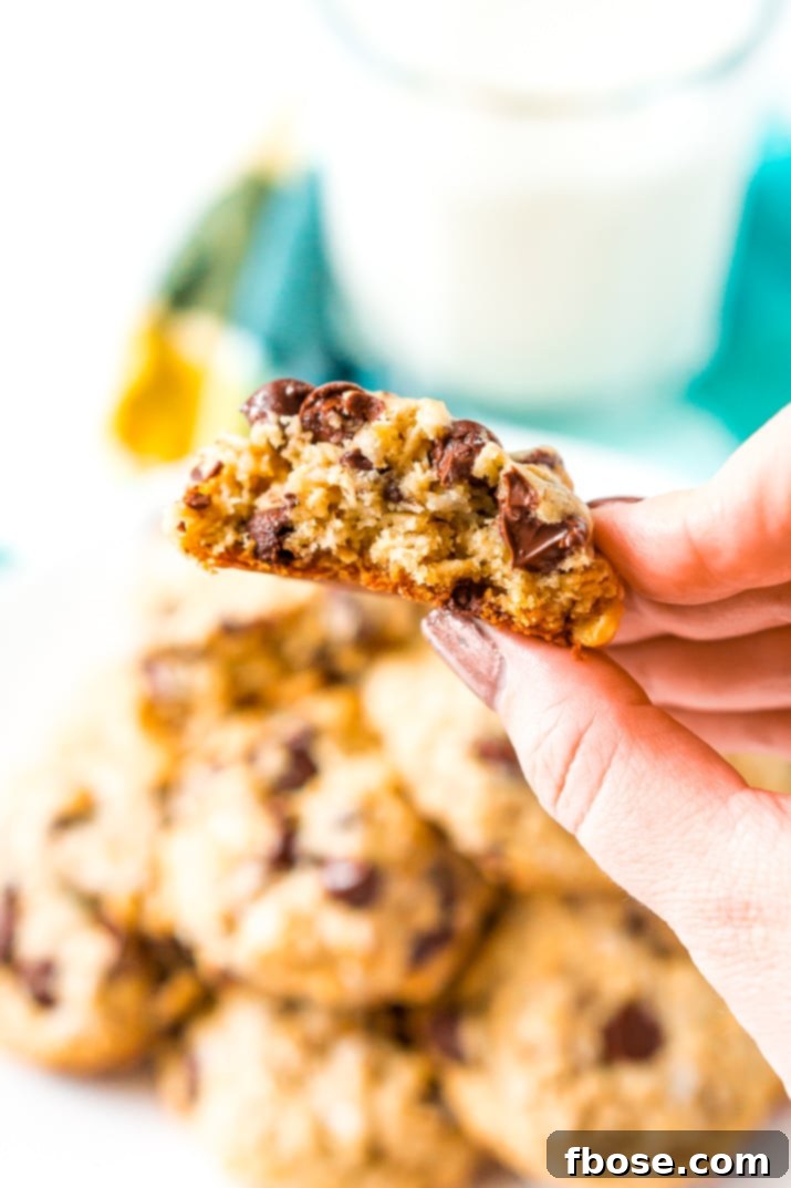 Woman's hand holding a Lactation Cookie that has had a bite taken out of it.