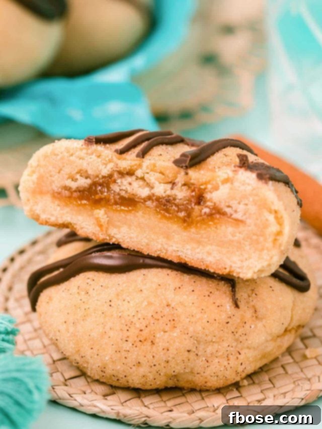 Two cookies stacked, one sliced open revealing the center stuffed with dulce de leche.