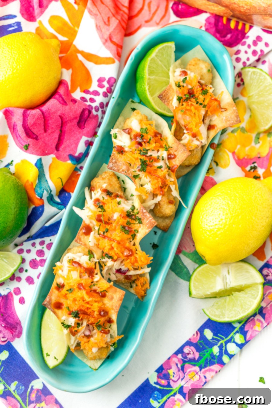 Close-up of Fish Stick Wonton Tacos with various condiments, inviting customization.