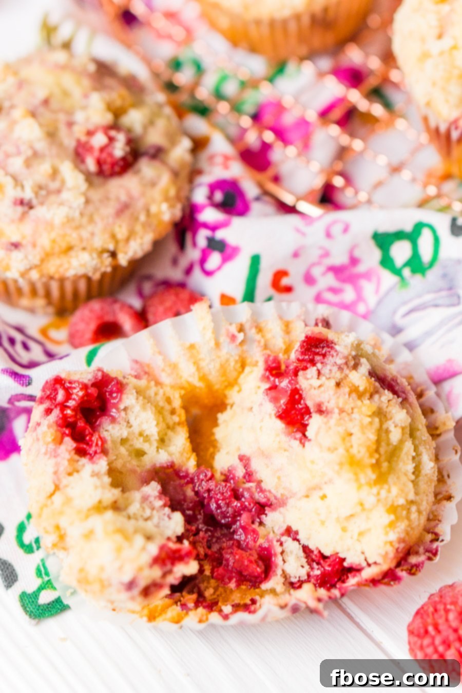 Close-up of a single Raspberry Muffin, emphasizing the fluffy interior and juicy raspberries.