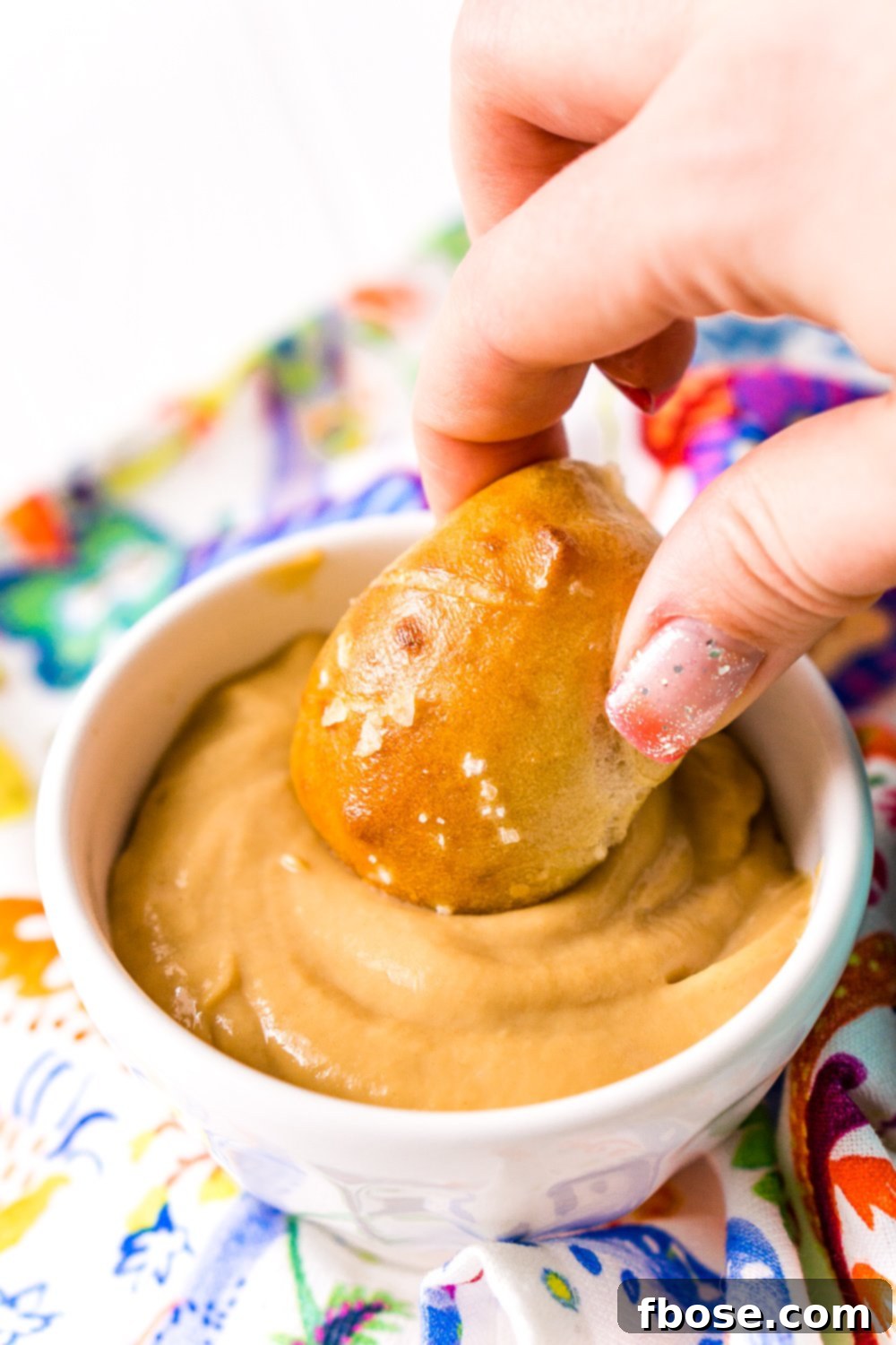 Woman's hand dipping pigs in a blanket into dipping sauce.
