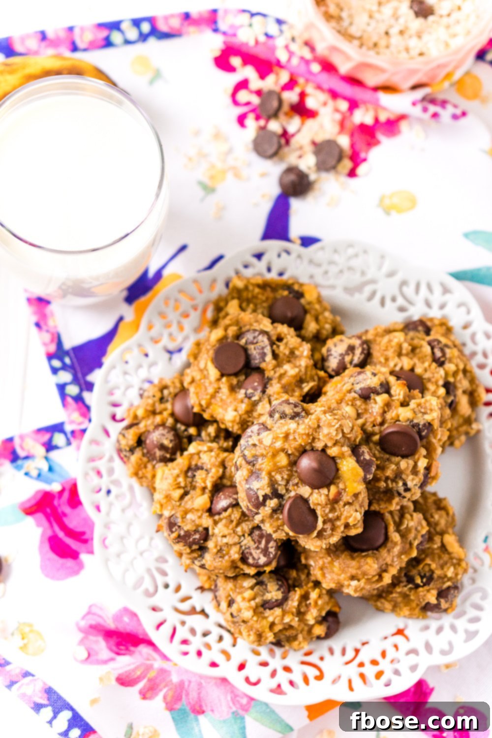 Overhead shot of Banana Chocolate Chip Cookies on white plate with glass of milk.