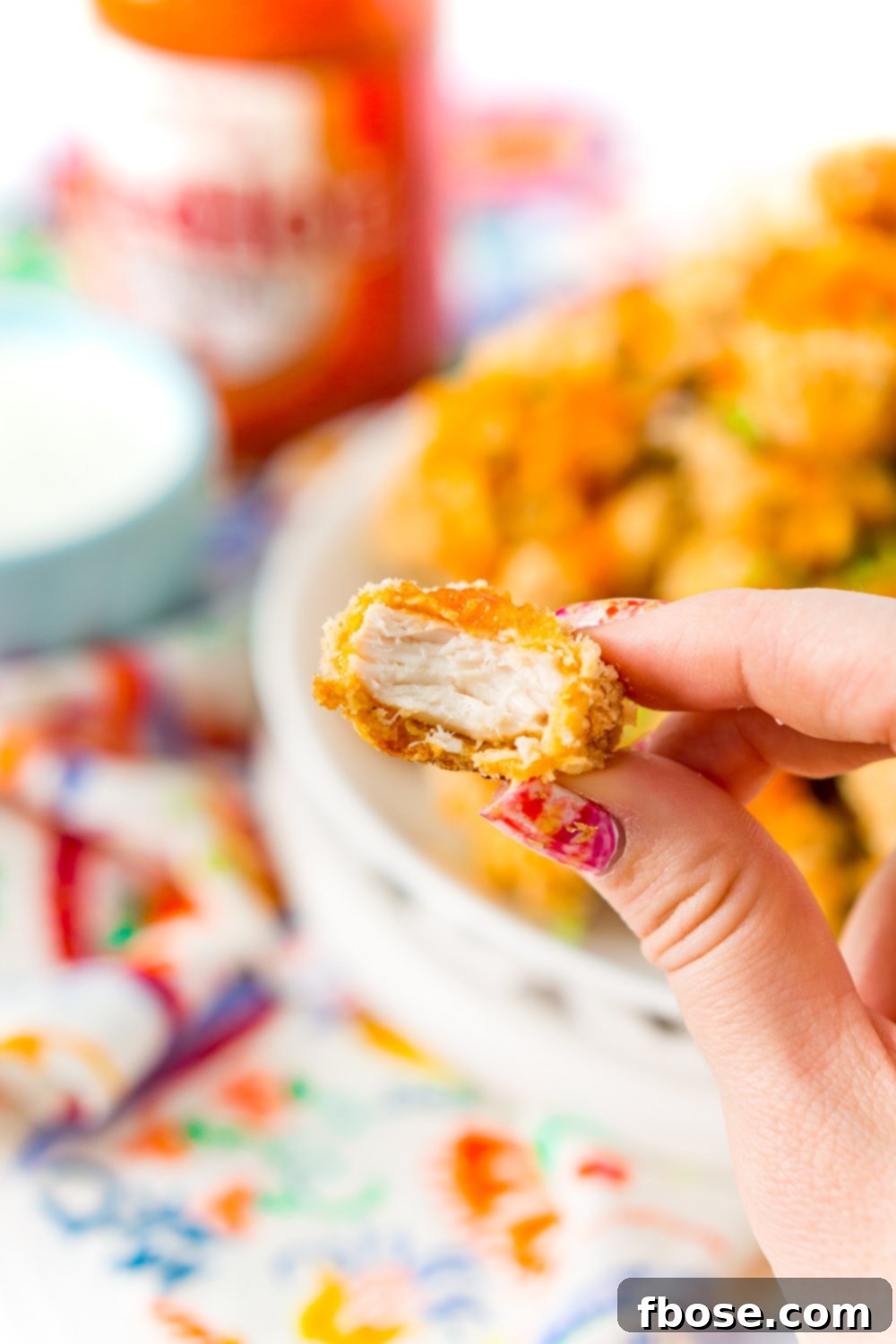 A Crispy Baked Chicken Wing bitten into being held by a woman's hand.