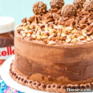 This Nutella Cake is a rich and indulgent dessert highlighting the delicious blend of chocolate and hazelnut! A moist chocolate cake coated in a decadent Nutella frosting and topped with Ferrero Rocher candy and chopped hazelnuts.