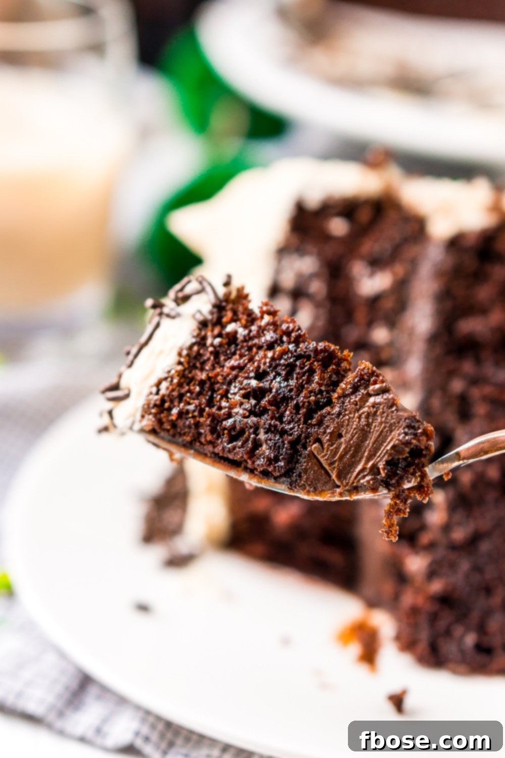 A delectable bite of Chocolate Guinness Cake on a fork, poised to be enjoyed, with a full slice of the cake subtly blurred in the background.