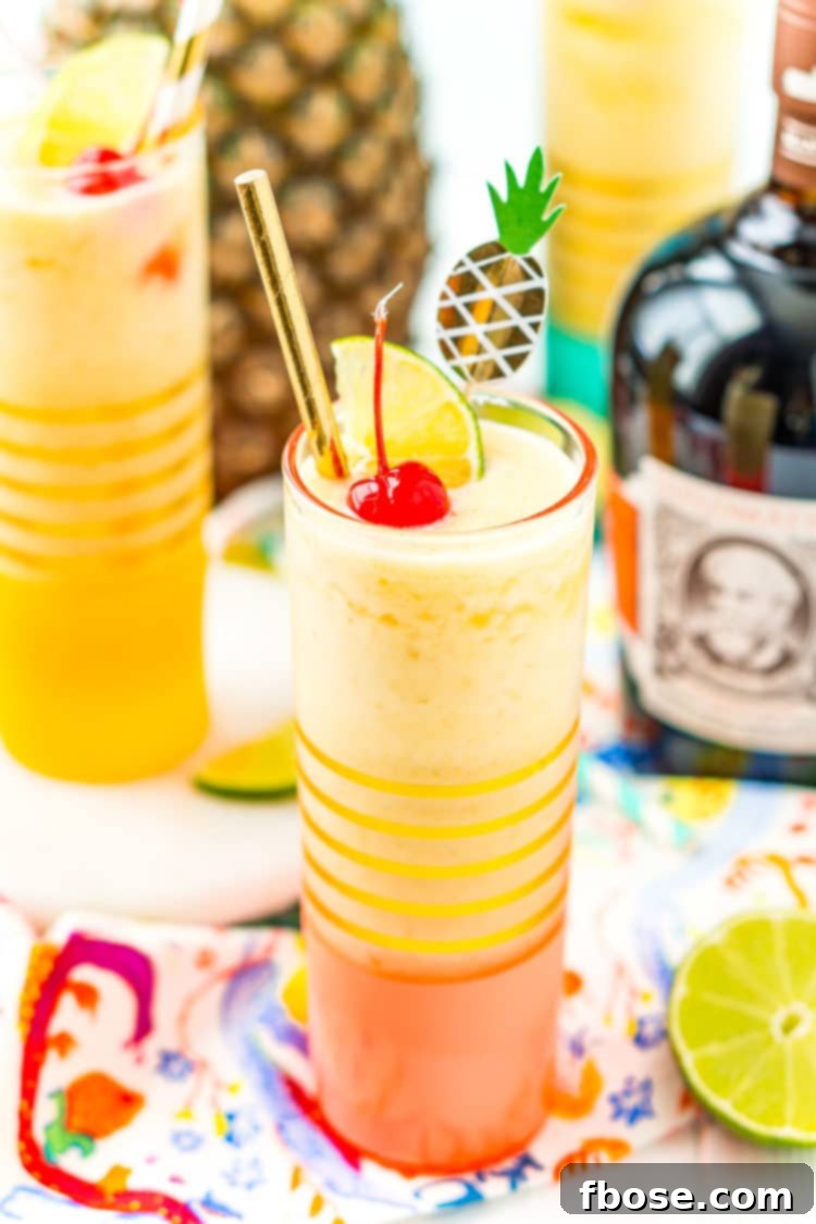 Tropical Pineapple Daiquiri 2 Two glasses filled with a frozen pineapple daiquiri cocktail, with a bottle of golden rum and a fresh pineapple in the background, evoking a tropical island theme.