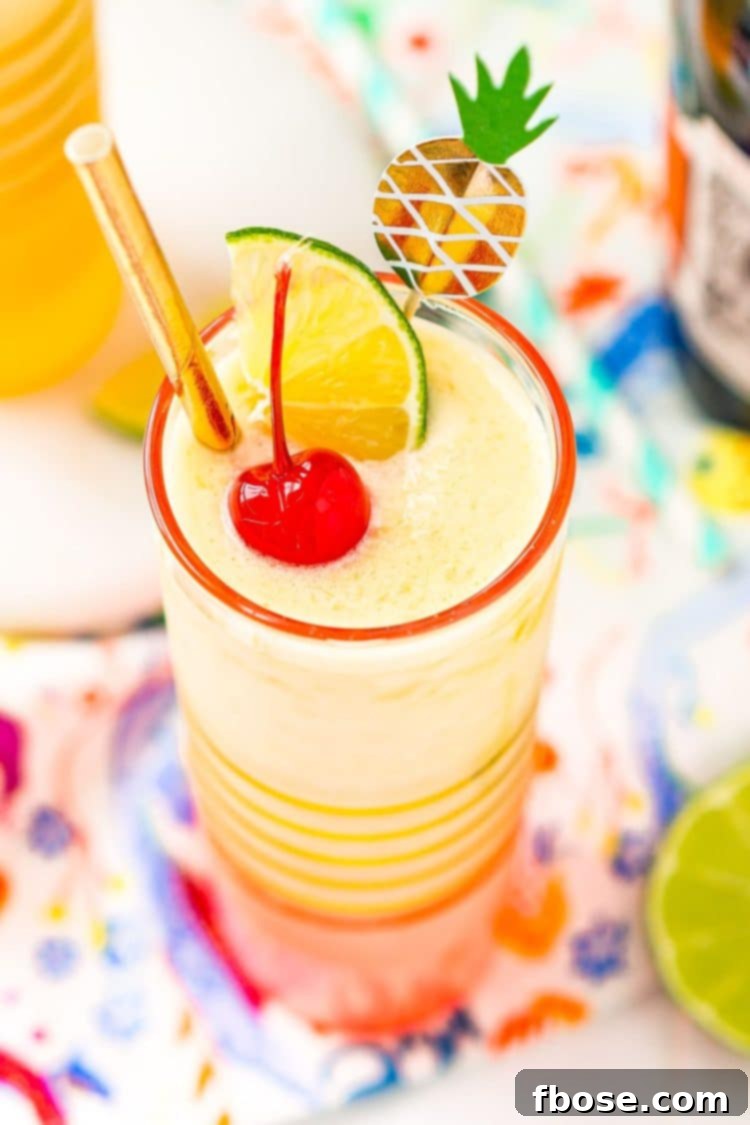 Tropical Pineapple Daiquiri 4 Close-up photograph of a vibrant pineapple daiquiri garnished with a bright maraschino cherry, a fresh lime wedge, and a elegant gold straw, emphasizing its festive and refreshing appeal.