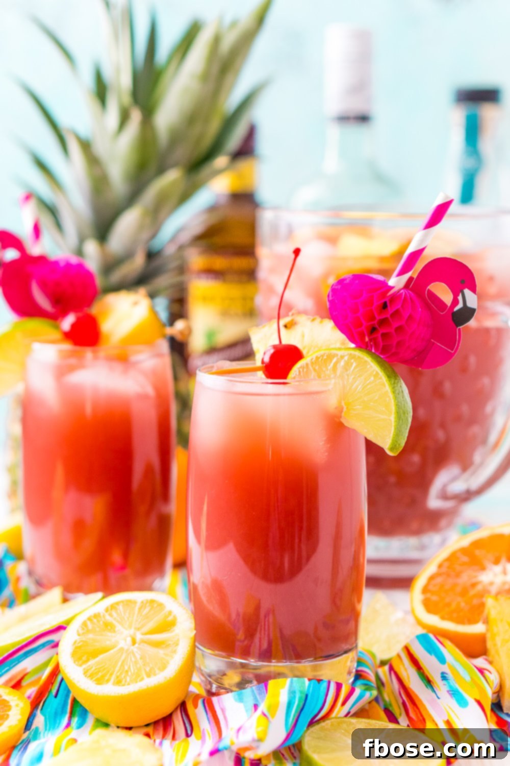 A vibrant pitcher of Rum Punch garnished with fresh fruit slices, ready to serve at a summer party. It combines orange, pineapple, lime, and lemon juice with ginger ale and three different kinds of rum.