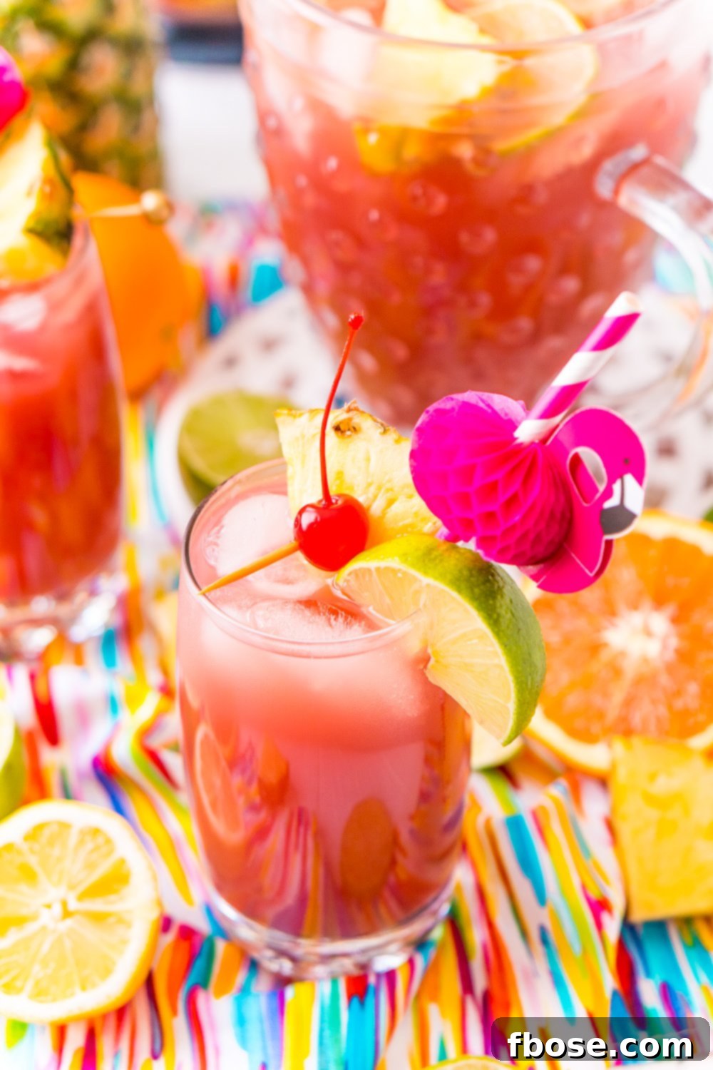 A single glass of Rum Punch, elegantly garnished with a maraschino cherry, a slice of lime, and a wedge of pineapple, served with a fun flamingo straw, emphasizing its tropical party appeal.