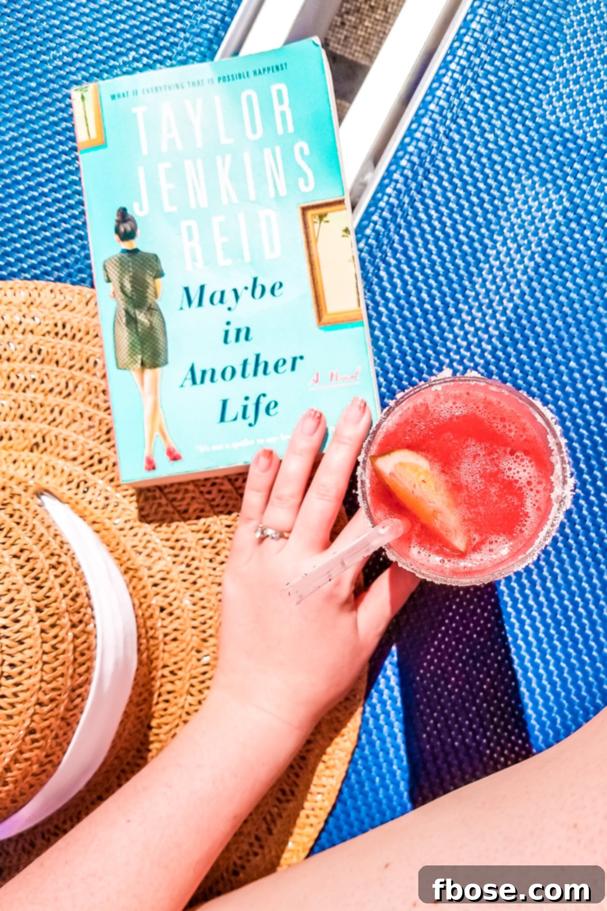Grand Turk Island: Your Port Adventure Guide 17 A stylish sunhat, an intriguing book, and a perfectly blended frozen cocktail rest invitingly on a bright blue lounge chair, symbolizing ultimate relaxation and leisure.