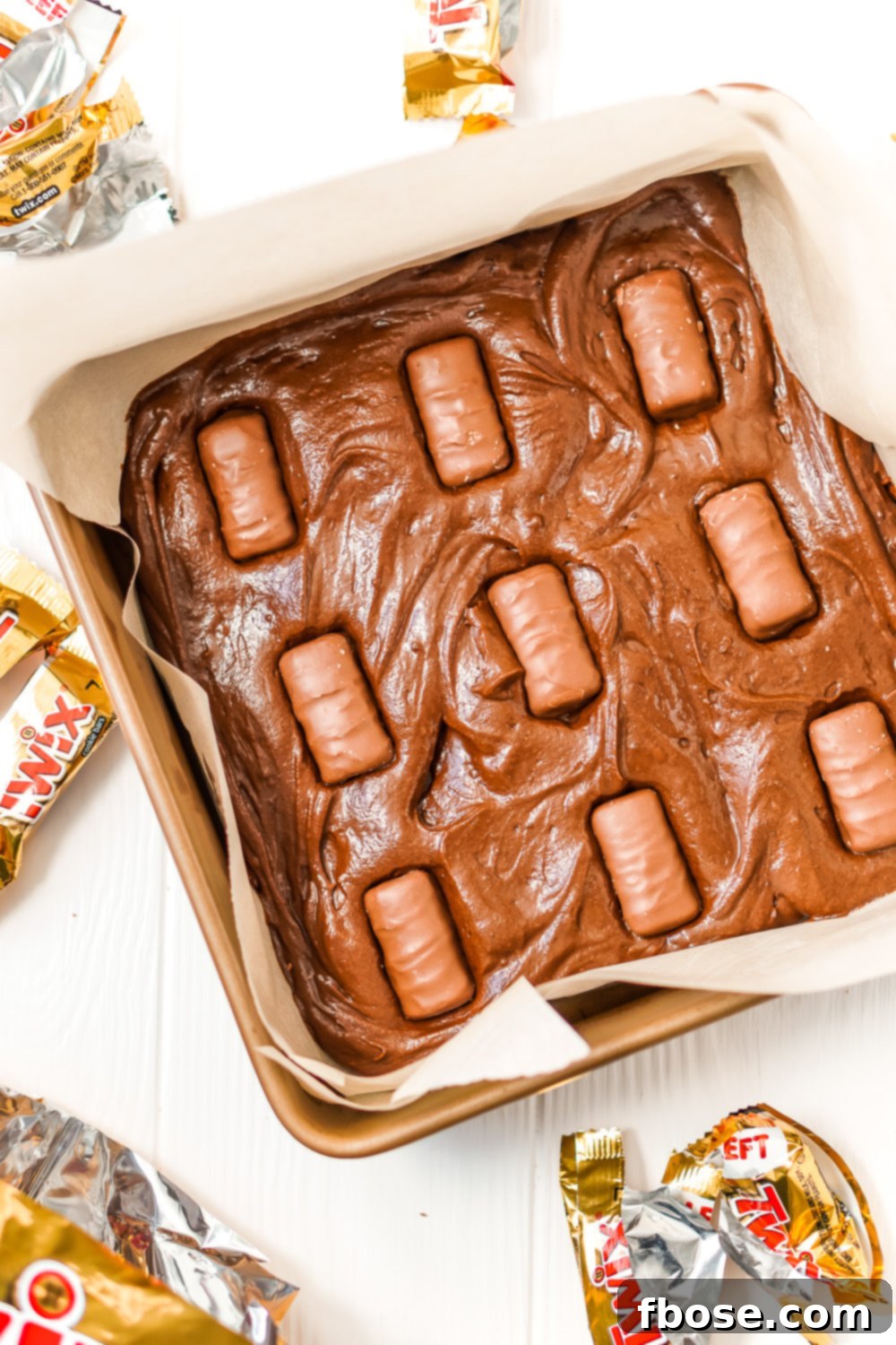 Twix Caramel Fudge Brownies 6 Unbaked brownie batter in baking dish with Twix bars pressed into the batter.