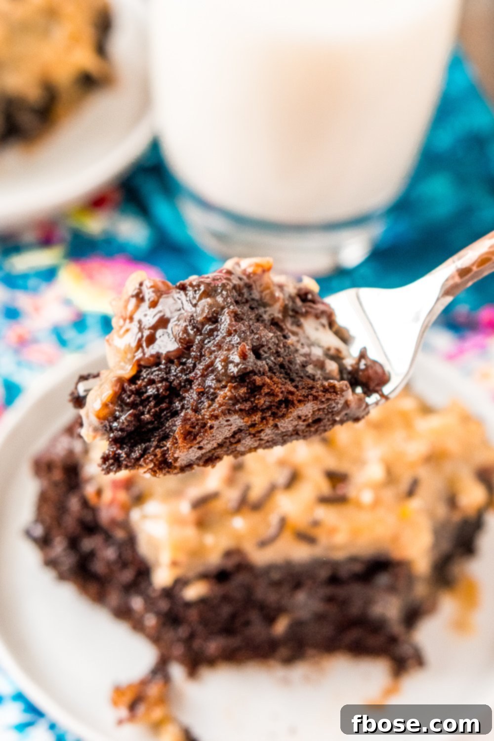 Fork with a bite of German Chocolate Poke Cake on it.