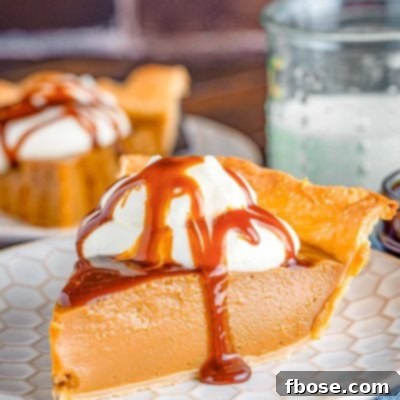 Close up photo of a slice of butterscotch pie on a white plate on a blue napkin.