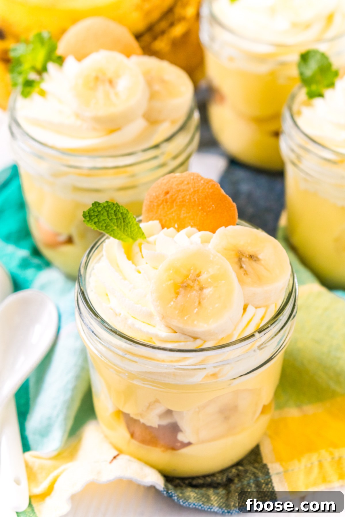 mini mason jars filled with banana pudding on a blue and yellow napkin.