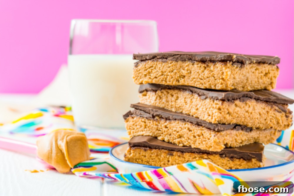 Peanut butter bars stacked on top of each other on a small white plate with spoon of peanut butter next to it and glass of milk in the background.