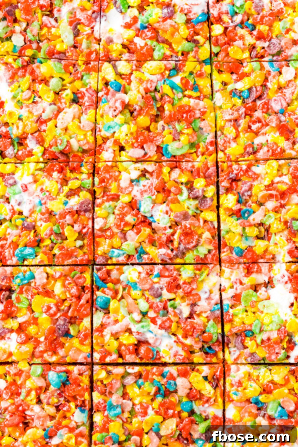 A close-up view of freshly sliced Fruity Pebbles Treats, revealing their colorful layers and the chewy texture of marshmallows and crisp cereal. Ready to be pulled apart and enjoyed.