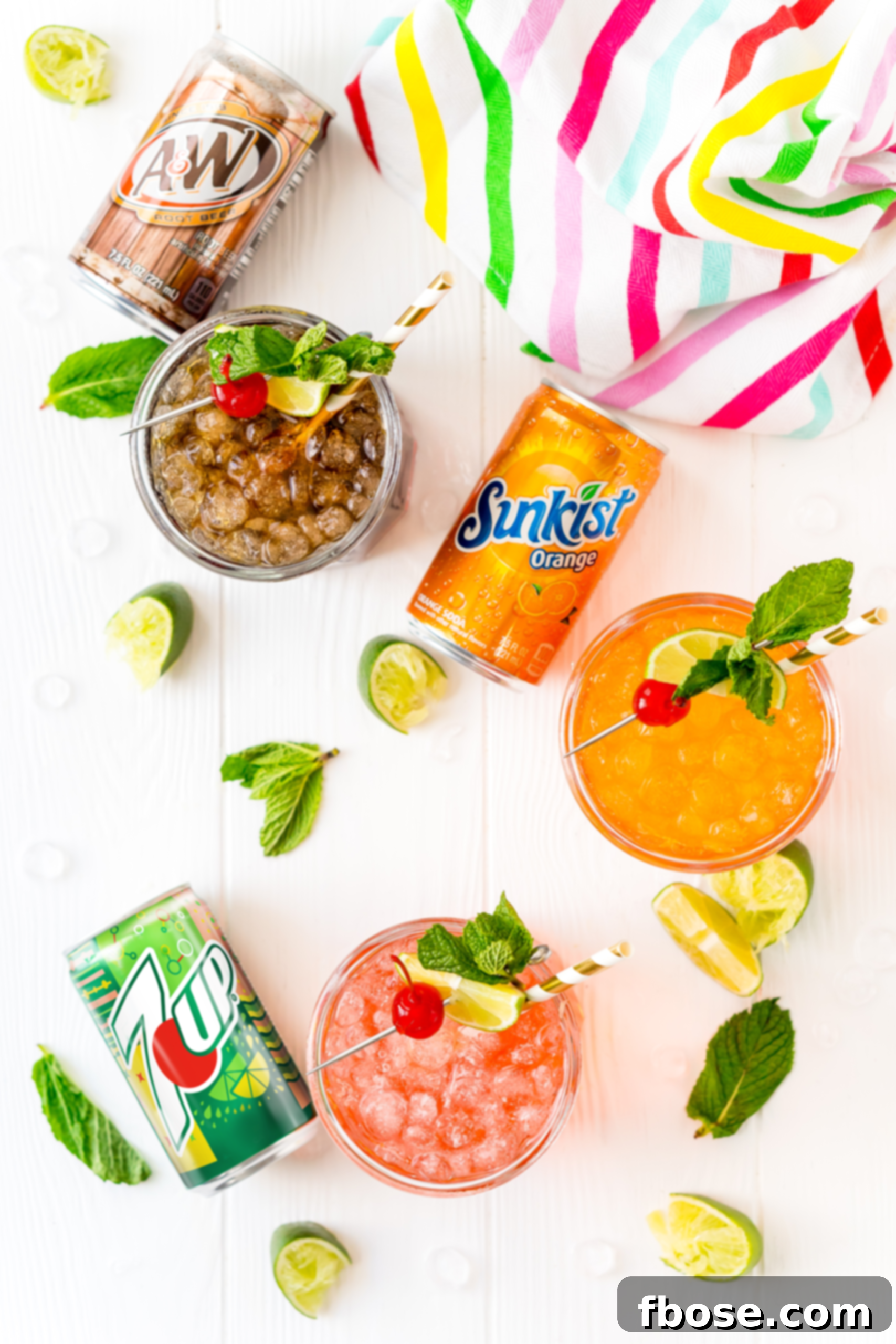 Simple Sips Three Ways 3 An overhead shot showcasing multiple mocktails in glasses, each accompanied by its respective soda can (7UP, A&W Root Beer, Sunkist), and garnished with fresh lime wedges, highlighting the customization options.