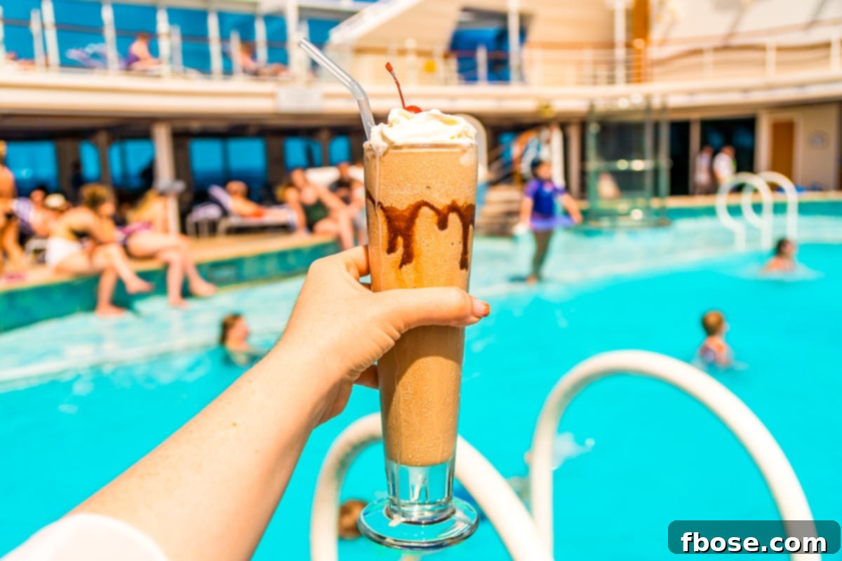 Woman's hand holding a frozen beverage by the pool on a cruise ship.