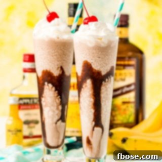 Frozen dirty banana drink in two glasses with bottles of rum and bananas in the background.