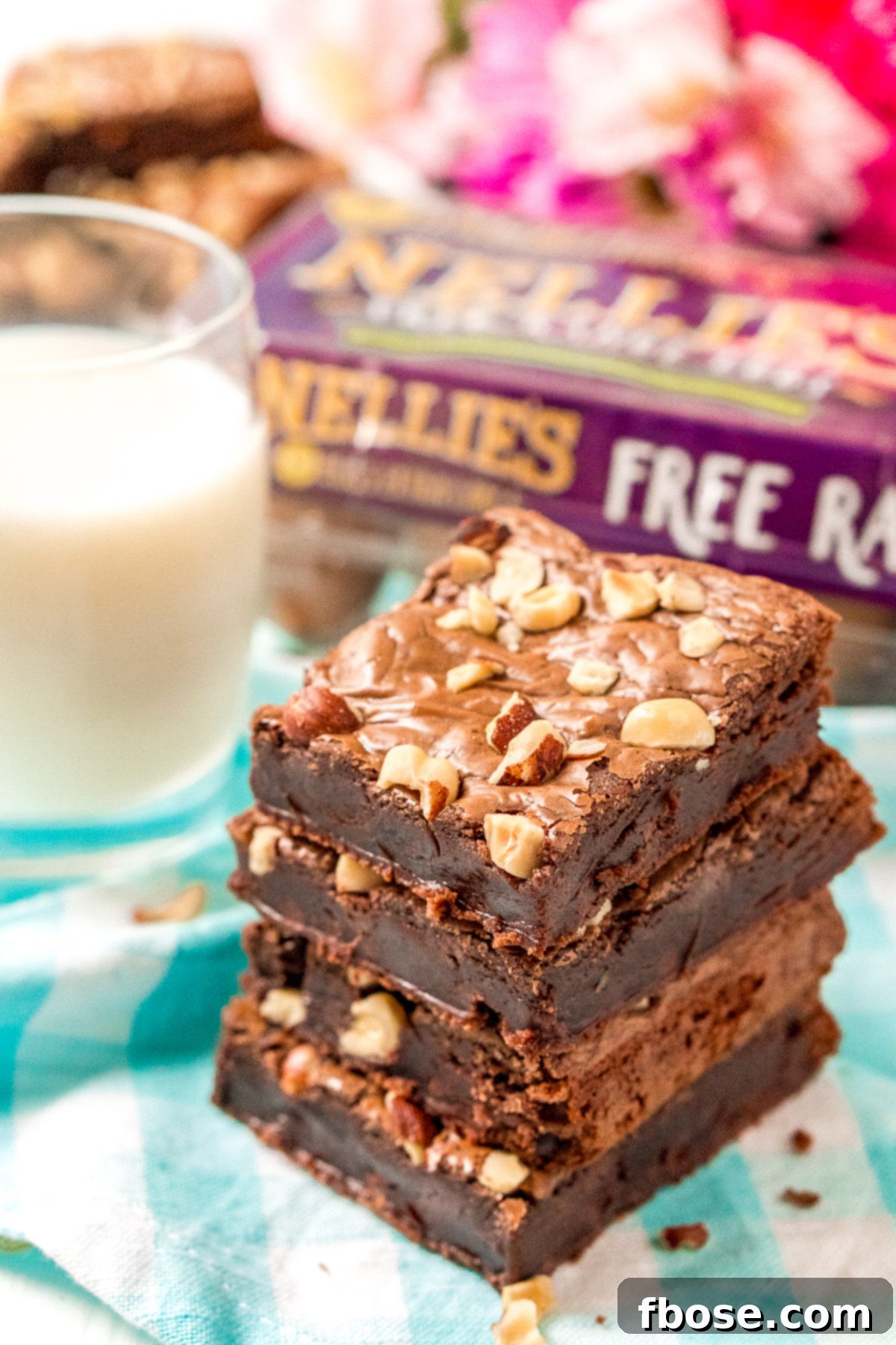 Stack of hazelnut brownies with a glass of milk in the background.