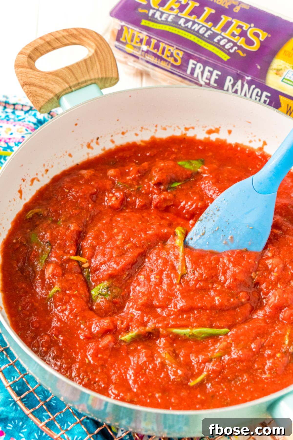 Spinach and basil being stirred into a pan of tomato sauce. Fresh spinach and basil leaves being gently folded into the rich tomato sauce, adding color, flavor, and nutrition.