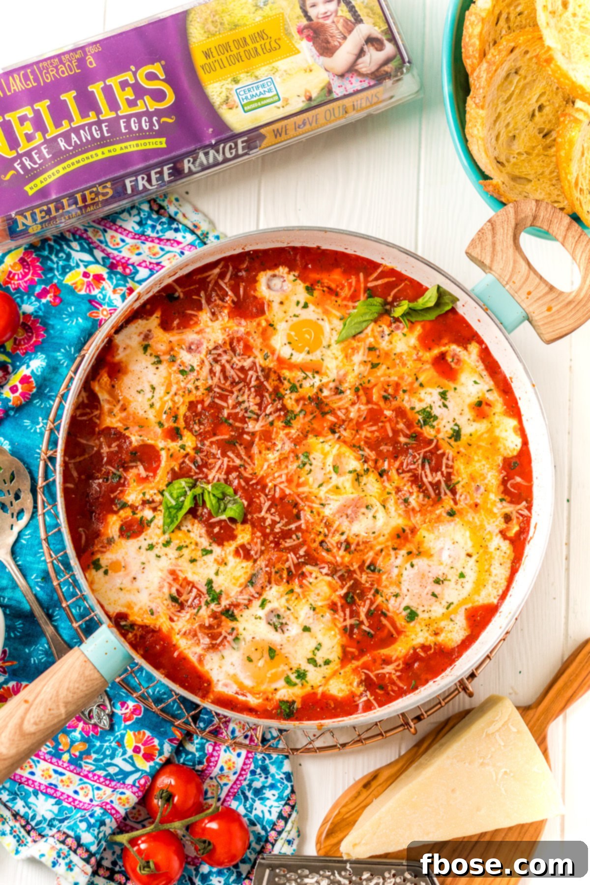 Overhead photo of Eggs In Purgatory in a skillet with additional ingredients scattered around it. An appetizing overhead view of the completed Eggs in Purgatory, garnished and ready to be served, surrounded by fresh ingredients.