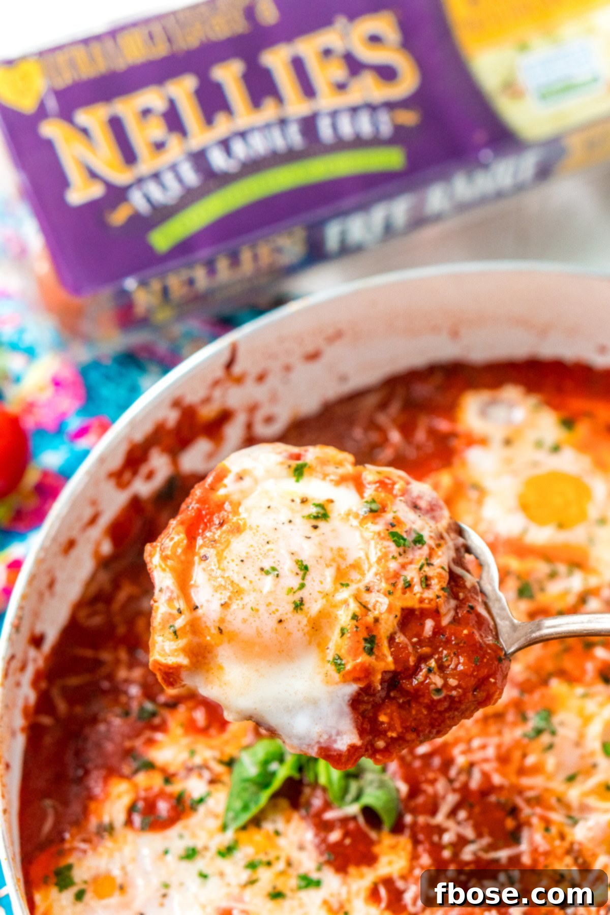 Poached egg being lifted out of Eggs In Purgatory with a serving spoon. A serving spoon carefully lifting a perfectly poached egg out of the rich Eggs in Purgatory, demonstrating its inviting texture.