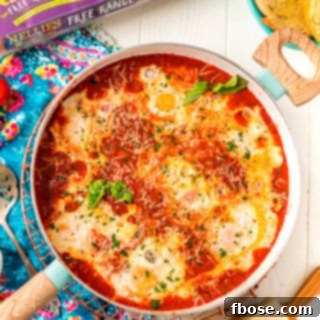 Overhead photo of Eggs In Purgatory in a skillet with additional ingredients scattered around it.