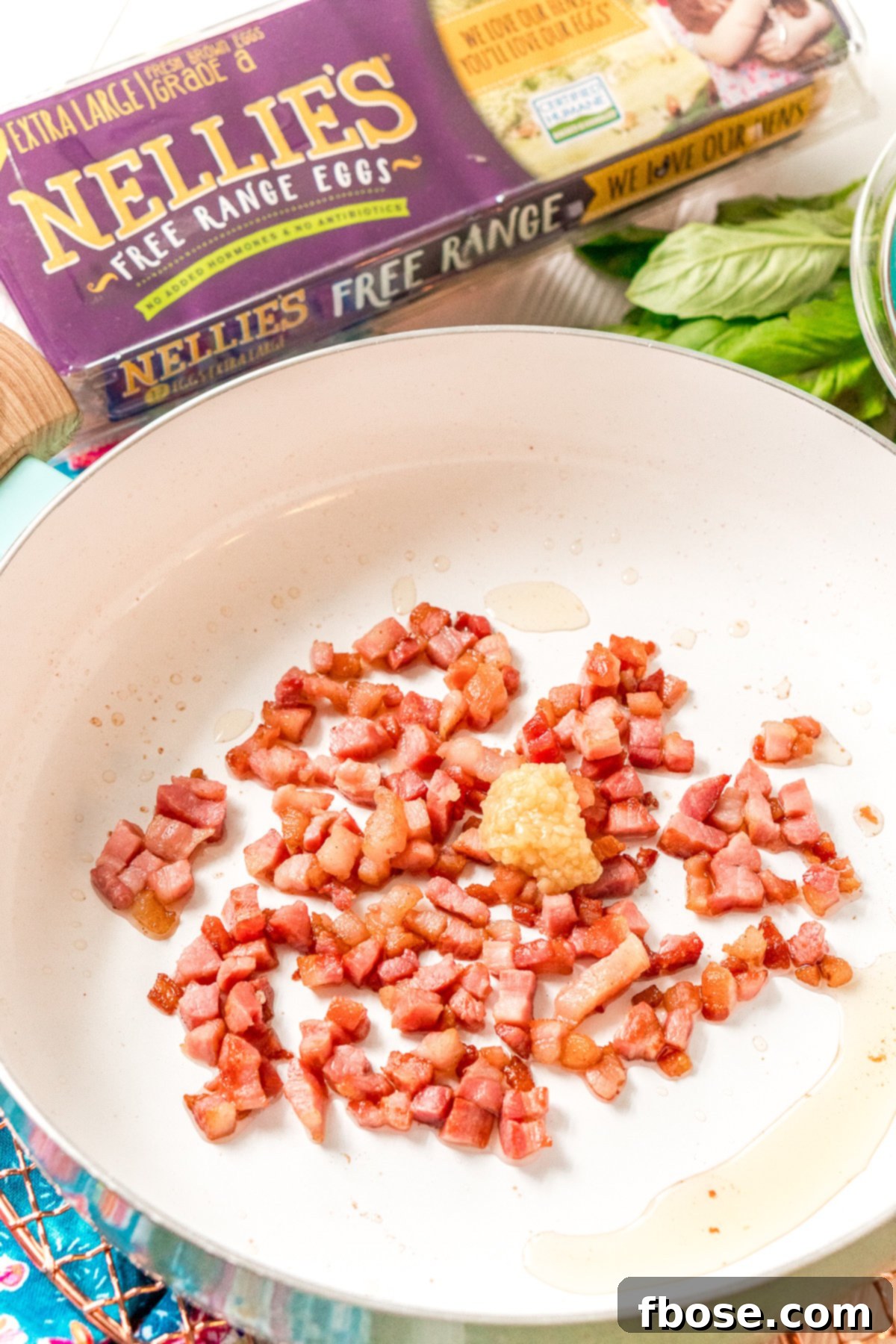 Pancetta and garlic being sauteed in a skillet. The initial step of cooking: pancetta and minced garlic sizzling in a skillet, creating an aromatic foundation for the dish.