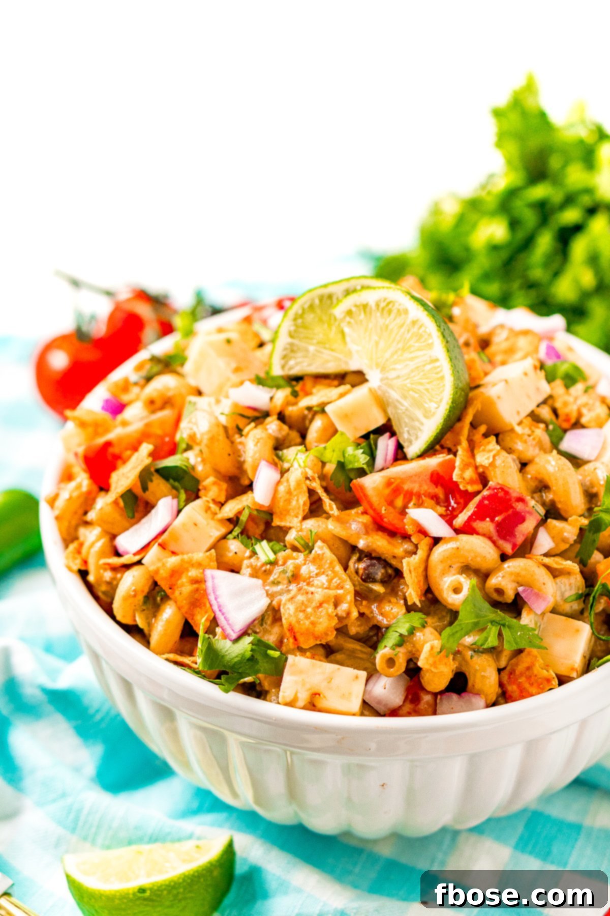A close-up of Taco Pasta Salad presented in a clean white bowl, resting on a stylish blue checkered napkin, emphasizing its vibrant colors and readiness for enjoyment.