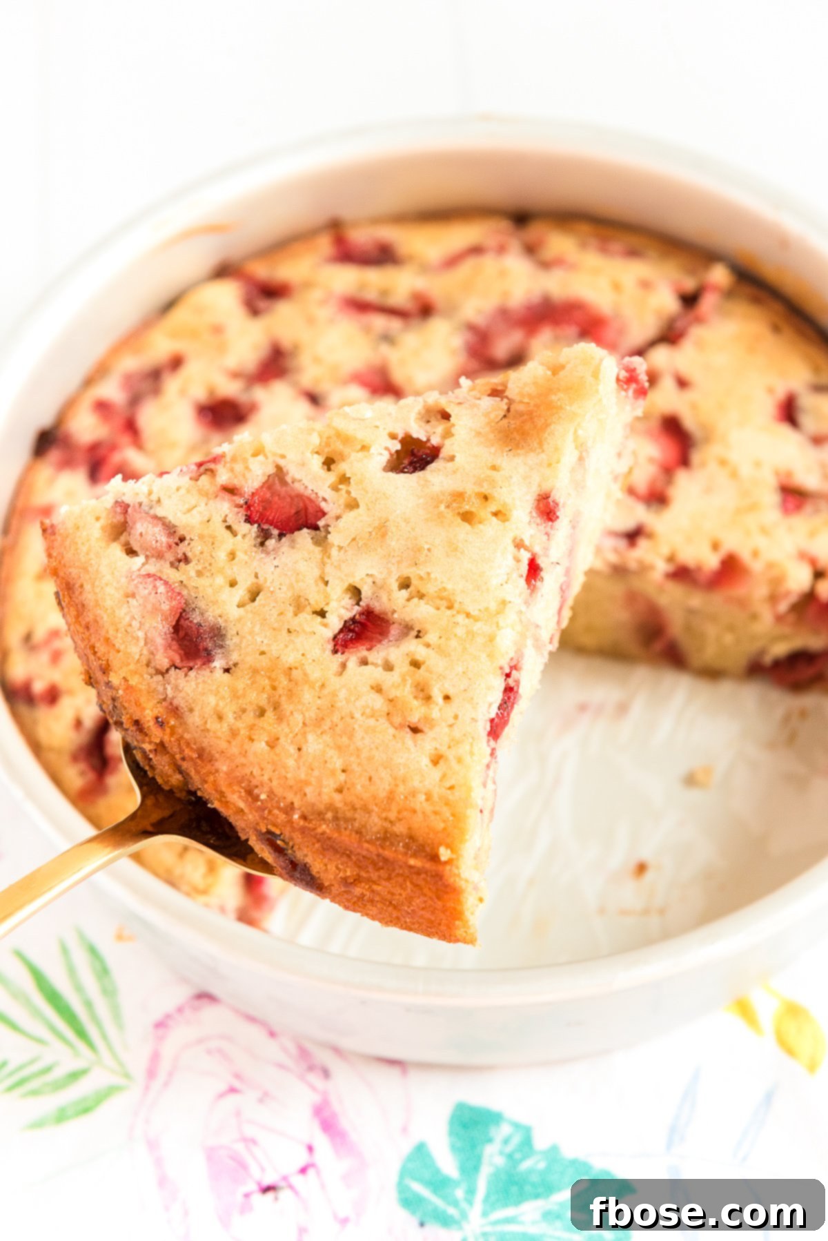 Slice of strawberry cake on a cake serving being removed from cake pan.