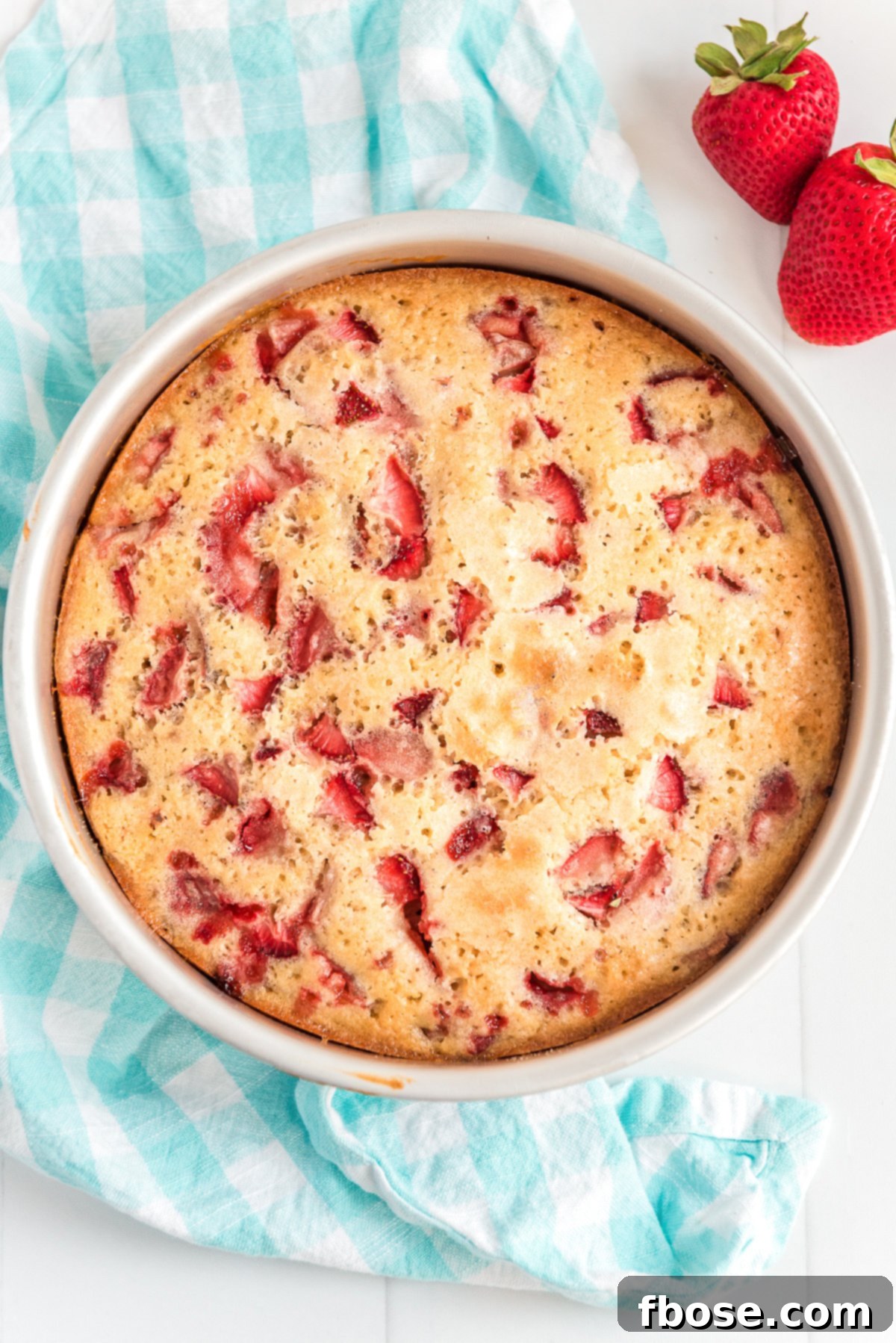 Overhead photo of baked strawberry cake on a blue napkin.