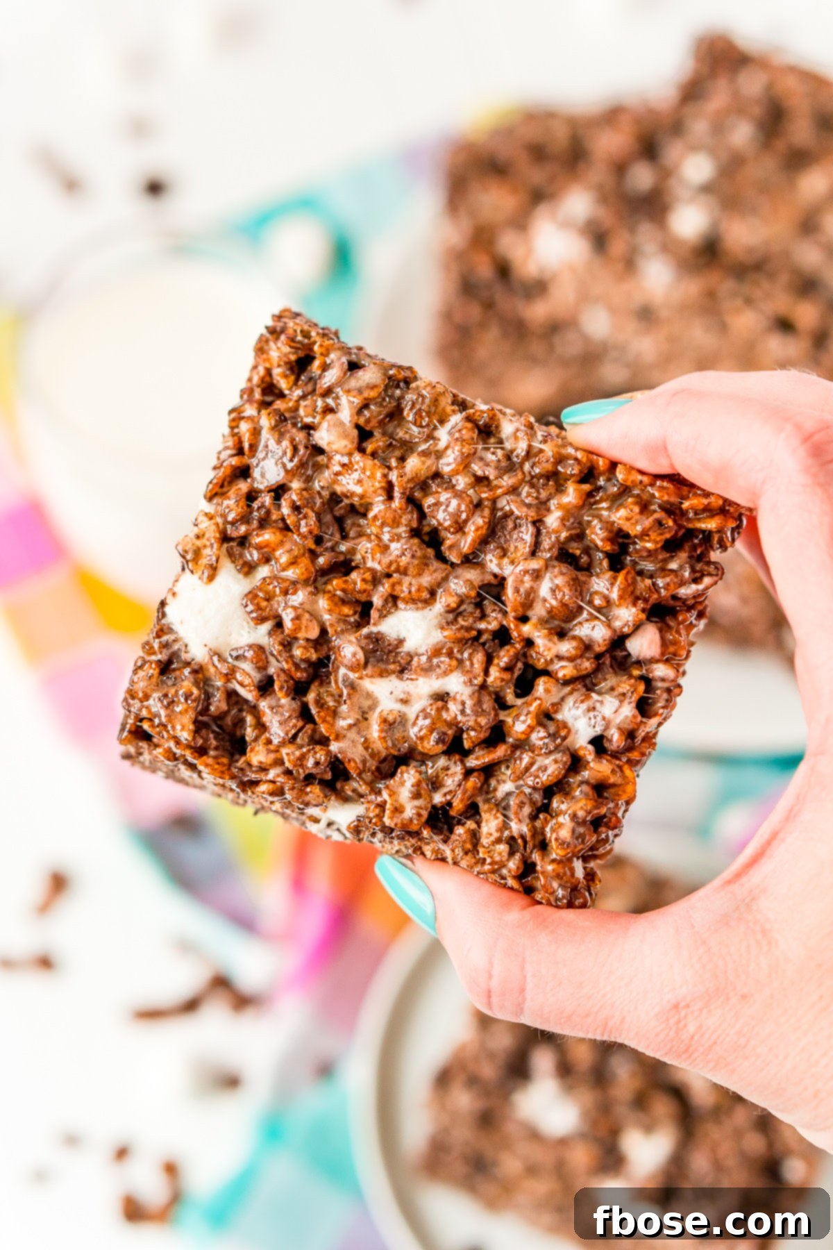 Cocoa Pebbles Crunch Bars 4 Woman's hand holding a chocolate rice krispie treat.